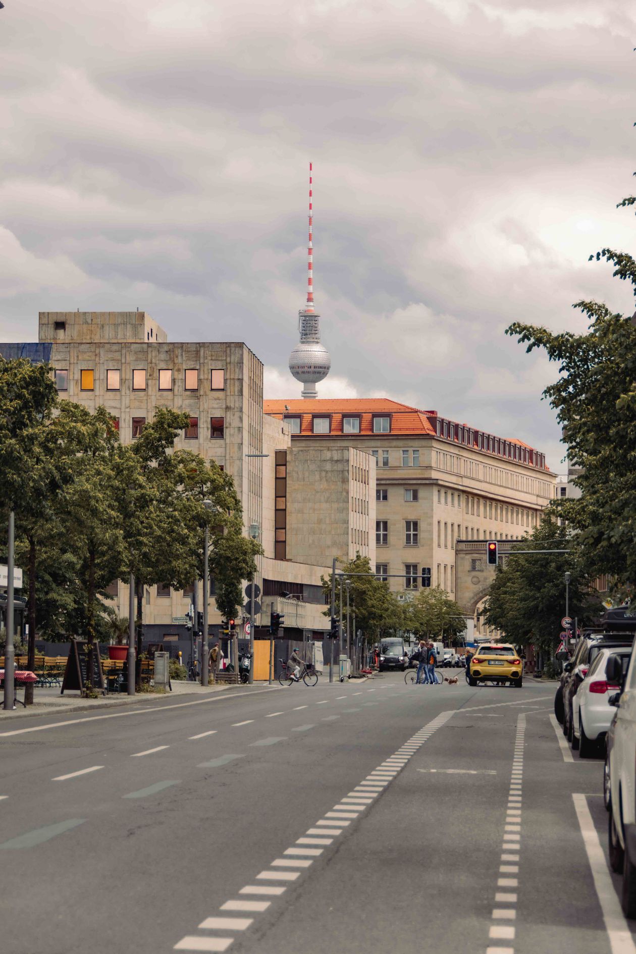 A wide Berlin avenue lined with buildings under a cloudy sky