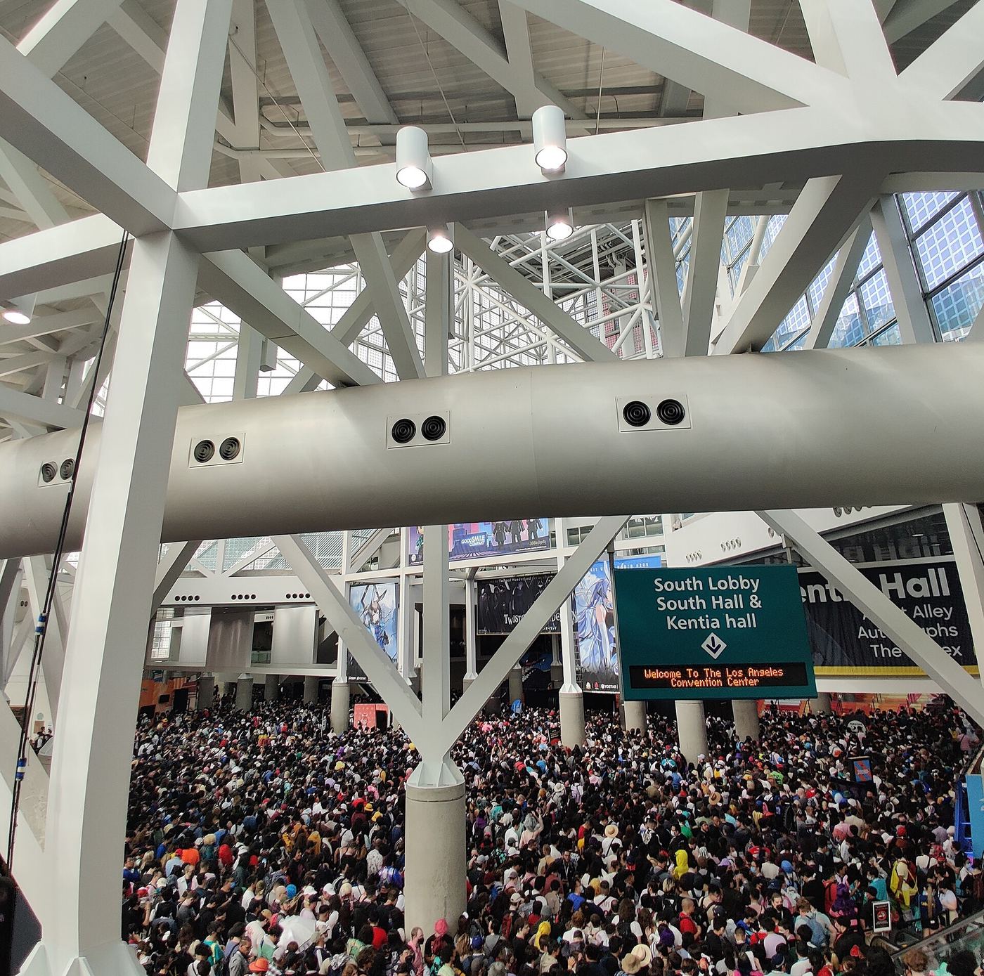 A packed anime convention hall filled with attendees, many in colourful cosplay